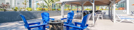 a patio with blue chairs and a fire pit