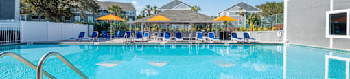 a large swimming pool with blue and yellow umbrellas in the background