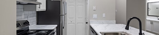 an empty kitchen with white cabinets and stainless steel appliances