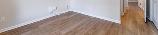 A room with a ceiling fan and light fixture, hardwood floors, and white walls.