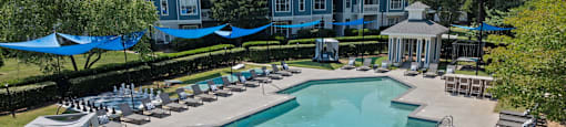 an aerial view of a resort style pool with lounge chairs and umbrellas