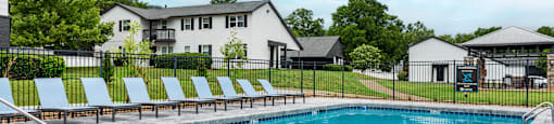 A large outdoor swimming pool with a black fence and sun loungers.