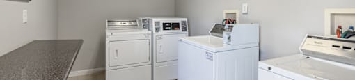 a laundry room with washes and dryers and a counter with a counter top