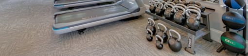 A gym with treadmills, exercise balls, and kettlebells.