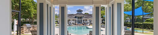 a covered porch with a pool and a house in the background