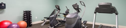 a gym with exercise equipment at the whispering winds apartments in pearland, tx