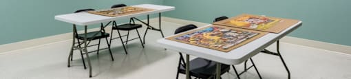 a room with two tables and chairs and three posters on the wall