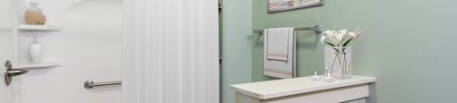 a small bathroom with green walls and a white shower curtain