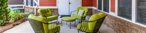 a covered patio with green chairs and a ceiling fan