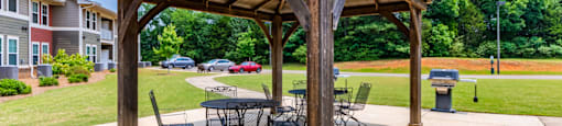a wooden pavilion with a table and chairs under it