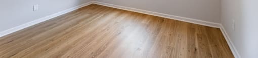 Empty room with a window and wooden floor.