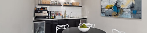 a dining area with a table and chairs and a kitchen in the background