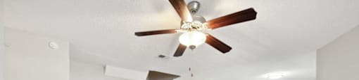 an empty living room with a ceiling fan and a fireplace