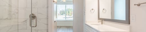 A white bathroom with a wooden floor and a marble shower.