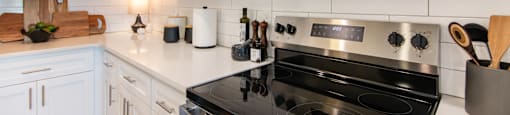 A modern kitchen with a black stove top oven and white cabinets.