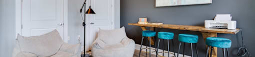 A room with a grey wall and a wooden floor with a white door and a table with four chairs.