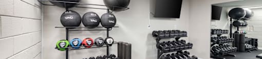 A gym with a variety of equipment including dumbbells, kettlebells, and weight plates.