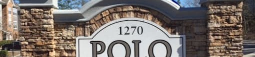 a sign for polo village on the side of a street