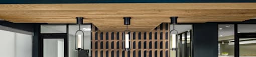 A modern clubhouse bar with white stools and a wooden backdrop at Boardwalk at Research Park apartments in Huntsville, AL.