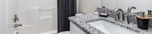 A bathroom with a granite countertop and a white bathtub.