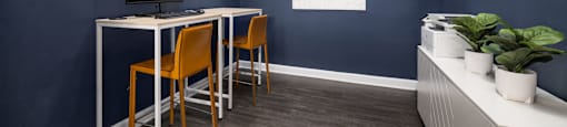 a home office with blue walls and a desk with orange chairs