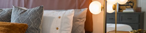 A bed with a brown headboard and a white pillow with a grey pillow with a white pillow with a brown pillow at 27Seventy Lower Heights apartments in Houston, TX.