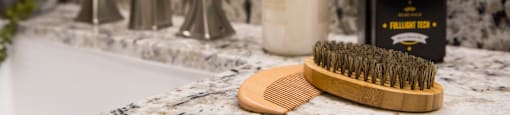 A bathroom sink with a brush and two bottles of soap at 27Seventy Lower Heights apartments in Houston, TX.