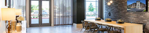 A modern clubhouse with a long table and chairs at 27Seventy Lower Heights apartments in Houston, TX.