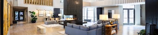 A spacious clubhouse with a grey sofa set and a wooden floor at 27Seventy Lower Heights apartments in Houston, TX.