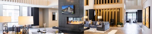 A modern clubhouse with a fireplace and a television on the wall at 27Seventy Lower Heights apartments in Houston, TX.