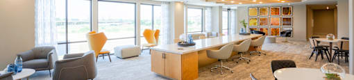 A common room with a variety of seating options and a long table at 27Seventy Lower Heights apartments in Houston, TX.