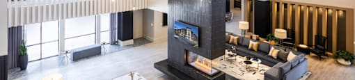 A modern clubhouse with a fireplace and a large rug at 27Seventy Lower Heights apartments in Houston, TX.