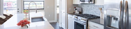 A modern kitchen with stainless steel appliances and a marble style island at 27Seventy Lower Heights apartments in Houston, TX.