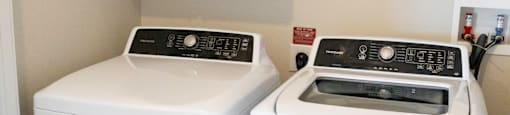 A white washing machine and dryer in a laundry room at 27Seventy Lower Heights apartments in Houston, TX.
