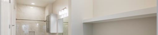An empty bathroom with a shower and tub combo and storage at 27Seventy Lower Heights apartments in Houston, TX.