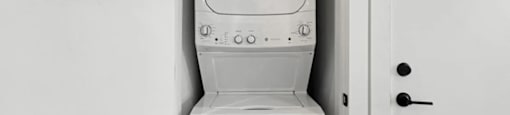 A white washing machine is sitting in a white door at Boardwalk at Research Park apartments in Huntsville, AL.