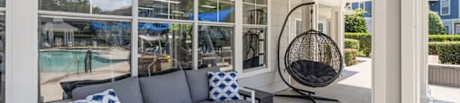a porch with a couch and a rocking chair and large windows