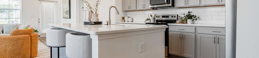 A kitchen with a white counter and bar stools.