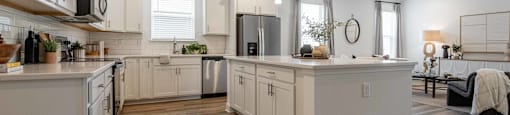 A modern kitchen with white cabinets and a wooden floor.