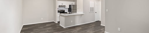an empty living room and kitchen with wood flooring