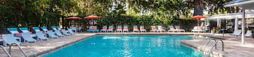 A large swimming pool surrounded by trees and lounge chairs.