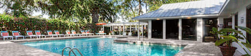 A pool surrounded by trees and a building.