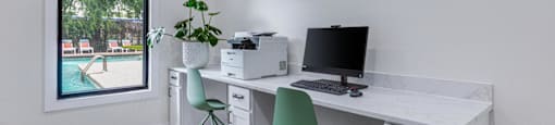 A white desk with a computer and a plant on it.