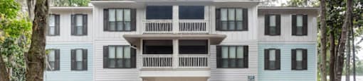 A white and blue building with a balcony in the middle.