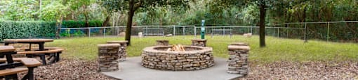 A park with a circular stone structure in the middle of a gravel path.