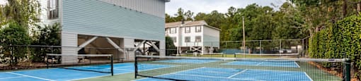 A tennis court is surrounded by a fence and a building.
