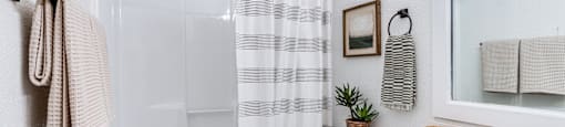a white bathroom with a striped shower curtain and a white toilet