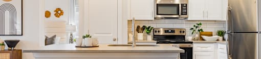 a kitchen with white cabinets and a counter top with two stools