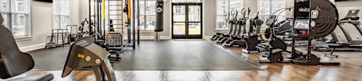 a gym with cardio machines and weights on a hard wood floor