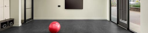 A red ball is placed on a black mat in a room with a flat screen TV mounted on the wall at Boardwalk at Research Park apartments in Huntsville, AL.